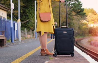 Vrouw op perron met trolley koffer wacht op de trein